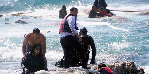FILE - In this Monday, April 20, 2015 file photo, Greek army Sgt. Antonis Deligiorgis, standing at left, rescues migrant Wegasi Nebiat from Eritrea, front left, from the Aegean sea, on the island of Rhodes, Greece. Deligiorgis was awarded the Cross of Excellency by Defense Minister Panos Kammenos at an Athens ceremony Monday, April 27, 2015 for his role in rescuing passengers from a ship carrying migrants from Turkey that sank after crashing into rocks a week ago. (Argiris Mantikos/Eurokinissi via AP, File) GREECE OUT