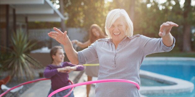 Older woman hula hooping in backyard