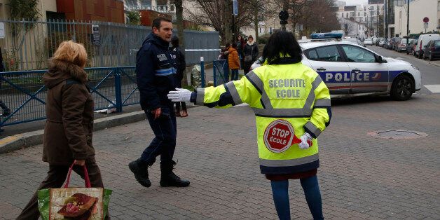 A municipal employee directs the trafic near a pre-school, after a masked assailant with a box-cutter and scissors who mentioned the Islamic State group attacked a teacher, Monday, Dec.14, 2015 in Paris suburb Aubervilliers. The assailant remains at large, and the motive for the attack is unclear, authorities said. (AP Photo/Michel Euler)