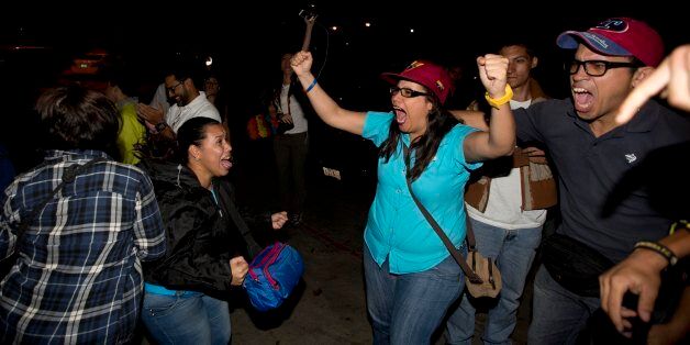 Opposition supporters celebrate in Caracas, Venezuela, early Monday Dec. 7, 2015. Venezuela's opposition won control of the National Assembly by a landslide on Sunday, delivering a major setback to the ruling party and altering the balance of power after 17 years of socialist rule.(AP Photo/Fernando Llano)
