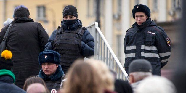 Russian police officers watch people as they line for an exhibition, in Manezh Square outside the Kremlin in Moscow, Russia, Friday, Nov. 20, 2015. In reaction to the recent attacks in France, Russian security forces across the country, are introducing additional measures to strengthen security. (AP Photo/Pavel Golovkin)