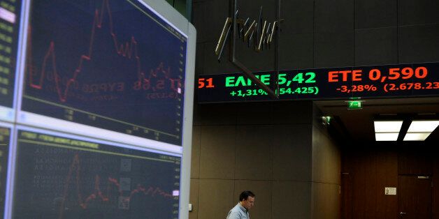 A stock exchange employee walks under a ticker showing share prices in Athens, on Monday, Sept. 21, 2015. Greek investors reacted guardedly to Sunday's victory of the left-wing Syriza party in parliamentary elections, and the main index was 1.4 precent down in afternoon trading. Syriza leader Alexis Tsipras is set to receive the formal mandate later Monday to form his coalition government. (AP Photo/Fotis Plegas G.)