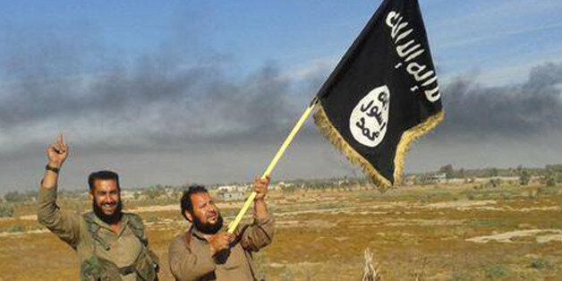 FILE - In this file photo released on Sunday, June 28, 2015, by a website of Islamic State militants, an Islamic State militant waves his group's flag as he and another celebrate in Fallujah, Iraq, west of Baghdad.The Islamic Stateâs gruesome rampage across the Middle East has united the world in horror but left it divided over how to refer to the group, with observers adopting different acronyms based on their translation of an archaic geographical term and the extent to which they want to needle the group. (Militant website via AP, File)