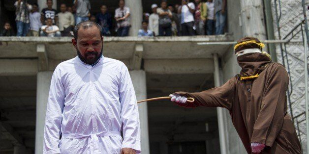 An Indonesian Sharia police whips a man during a public caning ceremony outside a mosque in Banda Aceh, capital of Aceh province on September 18, 2015. Three women and 14 men arrested for sexual offenses and gambling were caned in front of the mosque in full view of the public following the Friday prayer. Aceh is the only province of Indonesia that is enforcing the Islamic Sharia law and violators are punished by public caning. AFP PHOTO / CHAIDEER MAHYUDDIN (Photo credit should read CHA