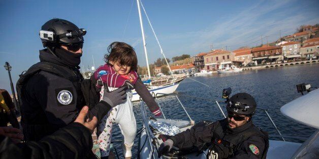 Members of the Frontex, European Border Protection Agency, from Portugal, hold a child at the port of Molyvos after a rescue operation near the Greek island of Lesbos, Tuesday, Dec. 8, 2015. In another incident six children have drowned after a rubber dinghy carrying Afghan migrants to Greece sank off Turkey's Aegean coast. Turkey has stepped up efforts to stop migrants from leaving to Greece by sea. (AP Photo/Santi Palacios)