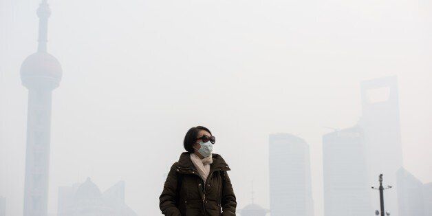 A woman wearing a face mask on a heavily polluted day stands along the Bund in front of the financial district of Pudong in Shanghai on December 15, 2015. According to local reports on December 14, Shanghai's environmental authority launched emergency measures against pollution after lingering smog was forecasted. The chronic haze blanketing northeastern China earlier this month was so thick that, unlike the Great Wall, it could be seen from outer space, according to satellite photographs from NASA. AFP PHOTO / JOHANNES EISELE / AFP / JOHANNES EISELE (Photo credit should read JOHANNES EISELE/AFP/Getty Images)