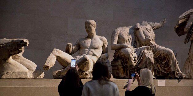 Women take pictures of a marble statue of a naked youth thought to represent Greek god Dionysos, center, from the east pediment of the Parthenon, on display during a media photo opportunity to promote a forthcoming exhibition on the human body in ancient Greek art at the British Museum in London, Thursday, Jan. 8, 2015. The exhibition, which is due to open on March 26, will feature around 150 objects including some from the museum's permanent Greek collection and other items from international collections. (AP Photo/Matt Dunham)