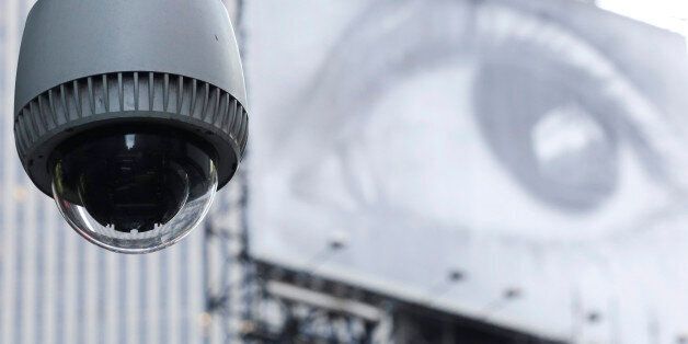 A security camera is mounted on the side of a building overlooking an intersection in midtown Manhattan, Wednesday, July 31, 2013 in New York. In the background is a billboard of a human eye. (AP Photo/Mark Lennihan)