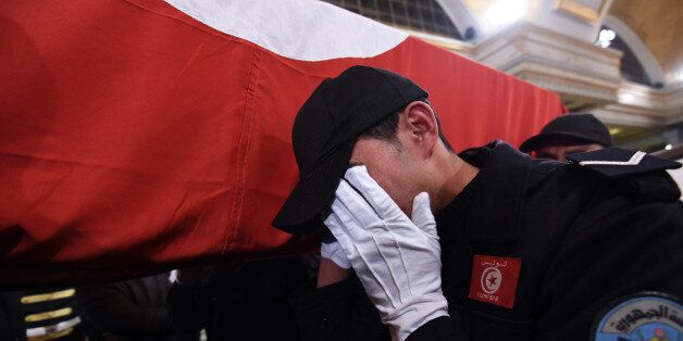 A Tunisian policeman mourns as he carries the coffin of a member of the presidential guards, who was killed in a bomb blast on a bus in central Tunis the previous day, during an official ceremony to honour those that were killed in the attack at Carthage Palace in the Tunisian capital on November 25, 2015. The Islamic State group claimed the deadly bombing of a presidential guard bus in the Tunisian capital in a statement shared on jihadist social media accounts. AFP PHOTO / FETHI BELAID / AFP / FETHI BELAID (Photo credit should read FETHI BELAID/AFP/Getty Images)