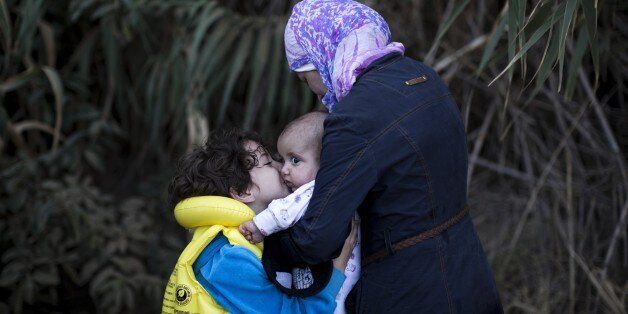 A syrian refugee family reacts after arriving on the shores of the Greek island of Lesbos after crossing the Aegean Sea from Turkey on a inflatable dinghy on September 11, 2015. The EU unveiled plans to take 160,000 refugees from overstretched border states, as the United States said it would accept more Syrians to ease the pressure from the worst migration crisis since World War II. AFP PHOTO / ANGELOS TZORTZINIS (Photo credit should read ANGELOS TZORTZINIS/AFP/Getty Images)