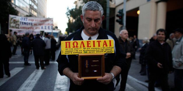 A Greek Army retiree holds his insignia and a for sale sign that reads