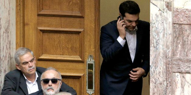 Greece's Prime Minister Alexis Tsipras speaks from his mobile phone during emergency Parliament session for the governmentâs proposed referendum in Athens, Saturday, June 27, 2015. Greece's place in the euro currency bloc looked increasingly shaky on Saturday, when eurozone countries rejected a monthlong extension to its bailout program and the prime minister called for a risky popular vote on the country's financial future. (AP Photo/Petros Karadjias)