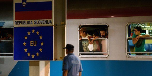 A police officer walks past migrants waiting in a train at the railway station, near the Slovenian-Croatian border in Dobova, Brezice, on September 17, 2015. Slovenia intends to reinforce its border with Croatia ahead of a possible influx of migrants seeking a new route into Europe's borderless Schengen area, the country's police chief said on September 16. Migrants have begun carving a new route into the Schengen area, travelling via Croatia, after neighbouring Hungary, overwhelmed by the refugee traffic, fenced off its own border with Serbia. AFP PHOTO / JURE MAKOVEC (Photo credit should read Jure Makovec/AFP/Getty Images)