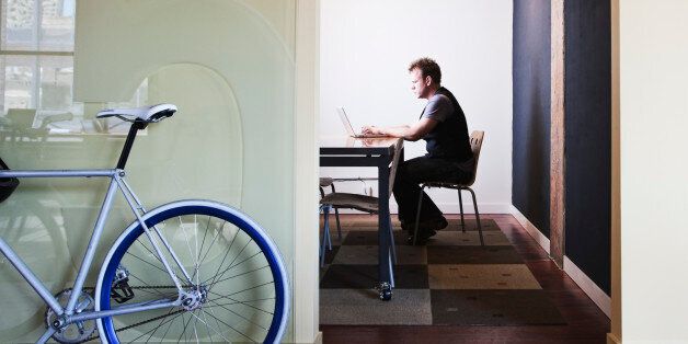 Bike leaning outside room with man on laptop