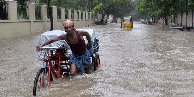 An Indian labourer pushes his cycle trishaw through floodwaters in Chennai on December 1, 2015, during a downpour of heavy rain in the southern Indian city. Heavy rains pounded several parts of the southern Indian state of Tamil Nadu and inundating most areas of Chennai, severely disrupting flights, train and bus services and forcing the postponment of half-yearly school exams. AFP PHOTO/STR / AFP / STRDEL (Photo credit should read STRDEL/AFP/Getty Images)
