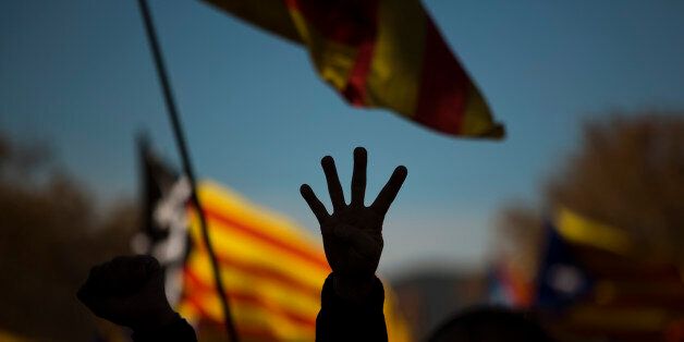A pro Independence demonstrator gestures - four fingers symbolizing the four bars of the Catalonian flag, during a demonstrations to show public support for the Parliament of Catalonia, in Barcelona, Spain, Sunday, Nov. 22, 2015. Prime Minister Mariano Rajoy made his first visit to the regional capital of Catalonia on Saturday following his administration's legal push to halt an effort secessionist regional parties to declare independence from Spain by 2017. (AP Photo/Emilio Morenatti)