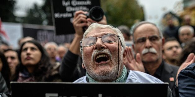 A member of journalism union holds a placard as he shouts slogans on November 29, 2015 in Istanbul during a demonstration after the arrest of their Editor in Chief. A court in Istanbul charged two journalists from the opposition Cumhuriyet newspaper with spying after they alleged Turkey's secret services had sent arms to Islamist rebels in Syria, Turkish media reported. Editor-in-chief Can Dundar and Erdem Gul, the paper's Ankara bureau chief, are accused of spying and 'divulging state secrets'.