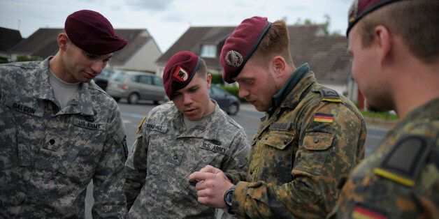 German Army soldiers show U.S. Army paratroopers from the 1st Squadron, 191st Cavalry Regiment, 173rd Airborne Brigade from Grafenwohr, Germany, a coin while waiting to meet with a French family as part of the 70th Anniversary of D-Day in Normandy, France, June 3, 2014. French citizens invited the U.S. Army and German Soldiers into their homes to show their appreciation for what soldiers did 70 years ago. (U.S. Air Force Photo/Staff Sgt. Sara Keller)