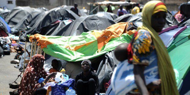 Illegal migrants from Niger sit next to their tents on May 14, 2014 after settling, some of them for more than one year, near the fruit market in the Algerian town of Boufarik, 35 km south of the capital Algiers in the Blida province. The Sahel-Sahara region has been plagued by jihadist violence and severe food shortages. Some Algerian newspapers articles have recently shown signs of racism against African migrants arriving in the country to flee violence and poverty back home. AFP PHOTO/FAROUK BATICHE (Photo credit should read FAROUK BATICHE/AFP/Getty Images)