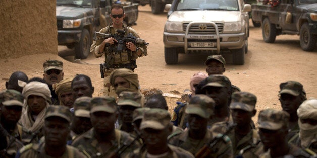 FILE - In this July 27, 2013 file photo, a French soldier stands watch behind Malian soldiers during a visit by the head of France's Operation Serval and Mali's army chief of staff to a Malian army base in Kidal, Mali. Eighteen months after France sent troops to Mali for what was meant to be a targeted operation against extremists, they are still there. And instead of leaving, theyâre about to expand their mission to fighting terrorism from the Atlantic coast to the Mediterranean. (AP Photo/Rebecca Blackwell, File)