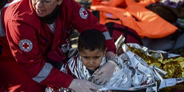 A Kurdish boy from the Syrian city of Afrin receives help after arriving on the Greek island of Lesbos along with other migrants and refugees, on November 17, 2015, after crossing the Aegean Sea from Turkey. At least eight people drowned when a boat carrying migrants from Turkey sank off the Greek island of Kos, the coastguard said on November 17, 2015. They were the latest of nearly 3,500 deaths at sea this year among people making desperate bids to flee war and poverty and to reach Europe, according to UN figures. European leaders tried to focus on joint action with Africa to tackle the migration crisis, as Slovenia became the latest EU member to act on its own by barricading its border. AFP PHOTO/BULENT KILIC (Photo credit should read BULENT KILIC/AFP/Getty Images)