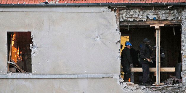 People work inside the damaged building of Wednesday's raid on an apartment in the Paris suburb of Saint-Denis, Thursday Nov.19, 2015. Abdelhamid Abaaoud, the Belgian extremist suspected of masterminding the deadly attacks in Paris died a day ago along with his female cousin in a police raid on a suburban apartment building.(AP Photo/Christophe Ena)