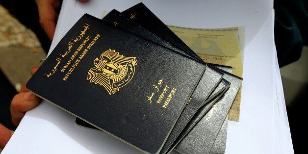 A Syrian refugee woman holds Syrian passports as she queues to apply for immigration outside the German Embassy on the northern outskirts of Beirut, on September 10, 2015. Lebanon, with a population of just four million, is hosting more than 1.1 million Syrian refugees. AFP PHOTO / JOSEPH EID (Photo credit should read JOSEPH EID/AFP/Getty Images)