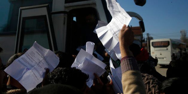 Migrants showing registration papers issued by Serbian authorities, try to get a seat on a bus in the southern Serbian town of Presevo, Monday, Nov. 16, 2015. Refugees fleeing war by the tens of thousands fear the Paris attacks could prompt Europe to close its doors, especially after police said a Syrian passport found next to one attackerâs body suggested its owner passed through Greece into the European Union and on through Macedonia and Serbia last month. (AP Photo/Darko Vojinovic)
