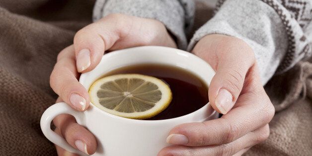 Hands with hot lemon tea cup, closeup