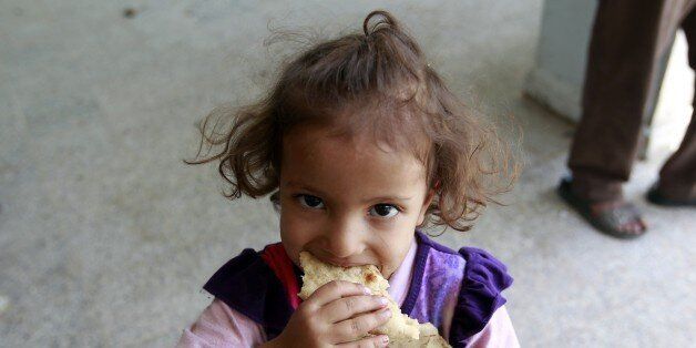 A displaced Yemeni child, who fled Saada province with her family due to fighting between Shiite Huthi rebels and forces loyal to Yemen's exiled President Abedrabbo Mansour Hadi, eats bread at a school turned into a shelter in the capital Sanaa on August 19, 2015. The United Nations warned of a 'developing famine' in Yemen, where more than half a million children are severely malnourished, and pressed for access to its war-torn regions. AFP PHOTO / MOHAMMED HUWAIS (Photo credit should read MOHAMMED HUWAIS/AFP/Getty Images)