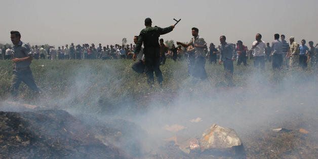 Smoke billows from the crash site of the Caspian Airlines plane, which fell into farmland near the city of Qazvin, northwest of Tehran, as an Iranian policeman asks people to leave the area on July 15, 2009. The Iranian airliner en route to neighbouring Armenia crashed killing all 168 people on board in the worst air disaster in Iran in recent years. AFP PHOTO/ISNA/SINA SHIRI (Photo credit should read SINA SHIRI/AFP/Getty Images)