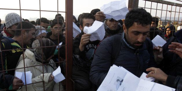 People hand in their documents for identification at the entrance of the transit center for refugees near the southern Macedonian town of Gevgelija, after crossing the border from Greece, Saturday, Nov. 14, 2015. Hundreds of thousands of migrants and refugees have passed the last few months through Macedonia as a part of the Balkan route, on their way to more prosperous European Union countries. (AP Photo/Boris Grdanoski)