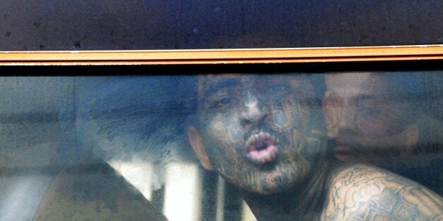 A gang member gestures from a bus as he is transferred to a high-security prison on April 24, 2015 in Izalco, El Salvador. About 400 feared gang members were transferred under heavy guard to a high-security prison in El Salvador in an attempt Friday to choke the criminal networks behind an upsurge in already sky-high violence. AFP PHOTO / Marvin RECINOS (Photo credit should read Marvin RECINOS/AFP/Getty Images)