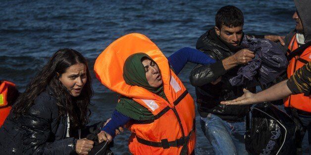 LESBOS ISLAND, GREECE - NOVEMBER 01: A group of refugees, succeeded to arrive the coast, are seen after a boat carrying refugees sank off the coast of Greece's Lesbos Island on November 01, 2015. Several other dead bodies washed ashore as well as some other refugee boats succeeded to arrive the island. (Photo by Javi Julio/Anadolu Agency/Getty Images)
