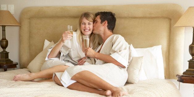 Young Couple Enjoying Champagne In Bedroom