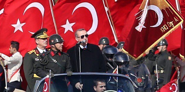 Turkish President Recep Tayyip Erdogan (R) speaks through a microphone next to Chief of the General Staff of the Turkish Armed Forces Hulusi Akar (L) as they are driven in a car past Turkish soldiers during a ceremony marking the 92nd anniversary of Republic Day on October 29, 2015 at the Ataturk Cultural Center in Ankara. AFP PHOTO / ADEM ALTAN (Photo credit should read ADEM ALTAN/AFP/Getty Images)