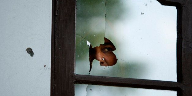 An Indian woman peeps from a glass door damaged in alleged firing from the Pakistan side at a residential area near the India-Pakistan international border in Kanachack village, about 25 kilometers (16 miles) from Jammu, India, Tuesday, Aug. 4, 2015. Indian and Pakistani border guards traded gunfire and mortar shells along their disputed border in the Himalayan region of Kashmir on Tuesday. (AP Photo/Channi Anand)