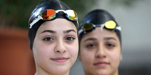 In this photo taken Monday, Nov. 9, 2015, Ysra Mardini, left, and her sister Sarah, right, from Syria pose for a photo during a training session in Berlin, Germany. Two months ago the sisters, who were once among Syria's brightest swimming stars, were swimming for their lives, after jumping off an inflatable boat that began taking on water carrying refugees to Greece. (AP Photo/Michael Sohn)