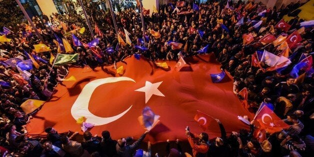 Supporters of Turkey's Justice and Development Party (AKP) hold a giant Turkish flag as they celebrate in Istanbul after the first results in the country's general election on November 1, 2015. Turkey's long-dominant Justice and Development Party (AKP) scored a stunning electoral comeback, regaining its parliamentary majority in a poll seen as crucial for the future of the troubled country. AFP PHOTO / OZAN KOSE (Photo credit should read OZAN KOSE/AFP/Getty Images)