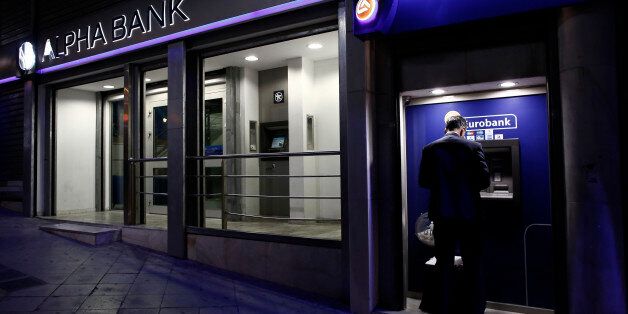 A customer uses an automated teller machines (ATM) operated by Eurobank Ergasias SA beside an Alpha Bank AE bank branch in Athens, Greece, on Tuesday, Nov. 3, 2015. Greece's four biggest banks may need as little as 1.2 billion euros ($1.3 billion) of new private funds to meet their expected contributions toward filling a capital shortfall, if they succeed in raising 3.2 billion euros through debt swaps. Photographer: Kostas Tsironis/Bloomberg via Getty Images