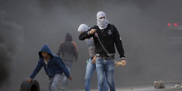 Palestinian protesters prepare to throw stones towards Israeli troops during clashes outside Ofer military prison near the West Bank city of Ramallah, Tuesday, Nov. 3, 2015. (AP Photo/Majdi Mohammed)