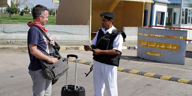 An Egyptian policeman checks a Russian tourist's passport at the main entrance to the Sharm el-Sheikh airport in Egypt on Saturday, Nov. 7, 2015. Egypt's Foreign Minister Sameh Shoukry complained on Saturday that Western governments had not sufficiently helped Egypt in its war on terrorism and had not shared relevant intelligence with Cairo regarding the Russian airplane that crashed last week in the Sinai, killing all 224 people onboard. (AP Photo/Ahmed Abd El-Latif)