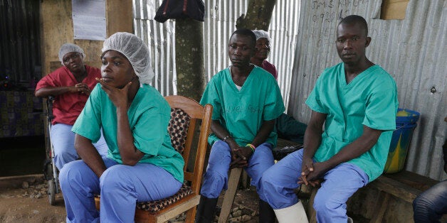 In this Monday, Aug. 10, 2015 photo, health workers take a break at the Kenema Government Hospital, where more than 40 health workers died of Ebola, in Kenema, eastern Sierra Leone. An Associated Press investigation has found a toxic mix of avoidable problems faced by Ebola responders, including weak leadership, shoddy supplies and infighting, exacerbated a chaotic situation at a critical front in the battle against the virus. (AP Photo/Sunday Alamba)