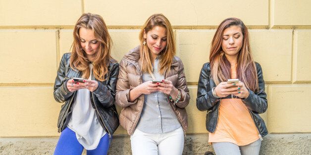 Girls typing on mobile phones - Three friends holding mobile phones and chatting - Youth,technology and comunication concepts