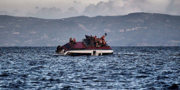Refugees and migrants call for help as their boat is ready to sink off the Greek island of Lesbos island while crossing the Aegean sea from Turkey on October 30, 2015. More than half a million people have arrived by sea in Greece this year seeking safety and a better life in Europe, while more than 3,200 people have died making the perilous crossing from Turkey. AFP PHOTO / ARIS MESSINIS (Photo credit should read ARIS MESSINIS/AFP/Getty Images)