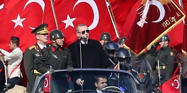 Turkish President Recep Tayyip Erdogan (R) speaks through a microphone next to Chief of the General Staff of the Turkish Armed Forces Hulusi Akar (L) as they are driven in a car past Turkish soldiers during a ceremony marking the 92nd anniversary of Republic Day on October 29, 2015 at the Ataturk Cultural Center in Ankara. AFP PHOTO / ADEM ALTAN (Photo credit should read ADEM ALTAN/AFP/Getty Images)