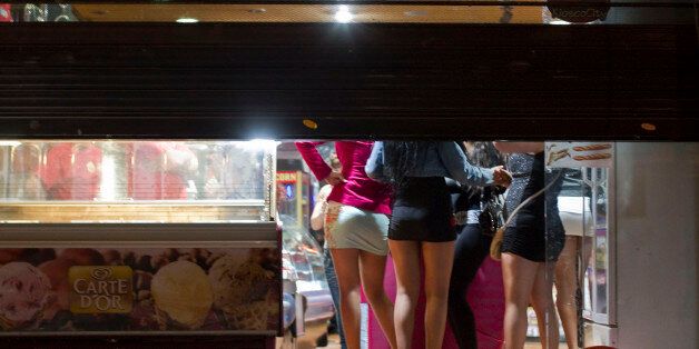 Prostitutes hide from riot police inside of a store during the eviction of a few activists who gathered at Puerta del Sol square to mark the anniversary of the