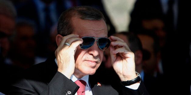 Turkish President Recep Tayyip Erdogan adjust his sunglasses before making a speech to his supporters, during an inauguration for an undersea pipeline to carry fresh water from Turkey to the breakaway Turkish Cypriot north of ethnically split Cyprus in Mirtou village, Saturday, Oct. 17, 2015. Erdogan and other Turkish officials symbolically turned open a large valve, starting the flow of water through the 107-kilometer (66.5-mile) pipeline at a ceremony at the Mediterranean town of Anamur, before leaving for Cyprus for a second ceremony in Cyprus marking the water's arrival. (AP Photo/Petros Karadjias)