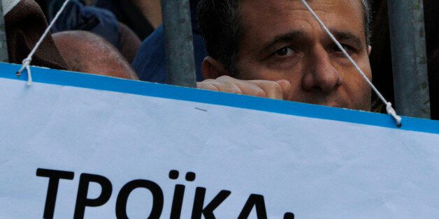 A protestor is seen behind a banner that reads in Greek