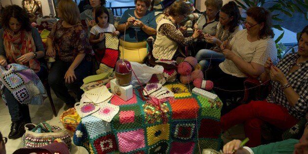 TO GO WITH AFP STORY BY DANIEL SILVAWomen knit blankets for Syrian people, at 'La Cafeteria' cafe in Villaverde del RÃo in on October 15, 2015. At home alone or hudled together in groups in cafes, women of all ages across Spain have furiously knitted blankets to send to war-torn Syria before cold weather starts in response to an online appeal for help. Every night for the past week, a team of some 20 women and girls have met in a cafÃ© in the heart of Villaverde del Rio, a town of white-washed houses near Seville, to finish their blankets and send them to a small NGO of Madrid, Syrian People Support Association. AFP PHOTO/ CRISTINA QUICLER (Photo credit should read CRISTINA QUICLER/AFP/Getty Images)